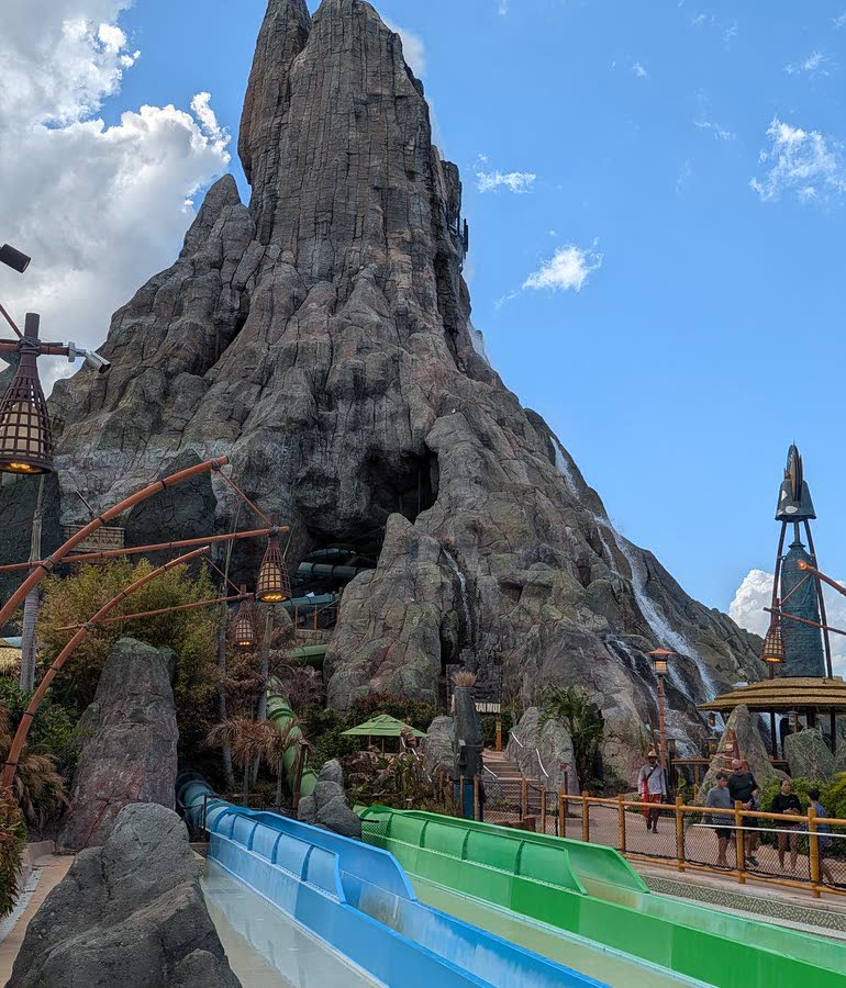 The Krakatau volcano rising over Volcano Bay, with the blue and green Kala & Tai Nui body slide chutes emerging from its base