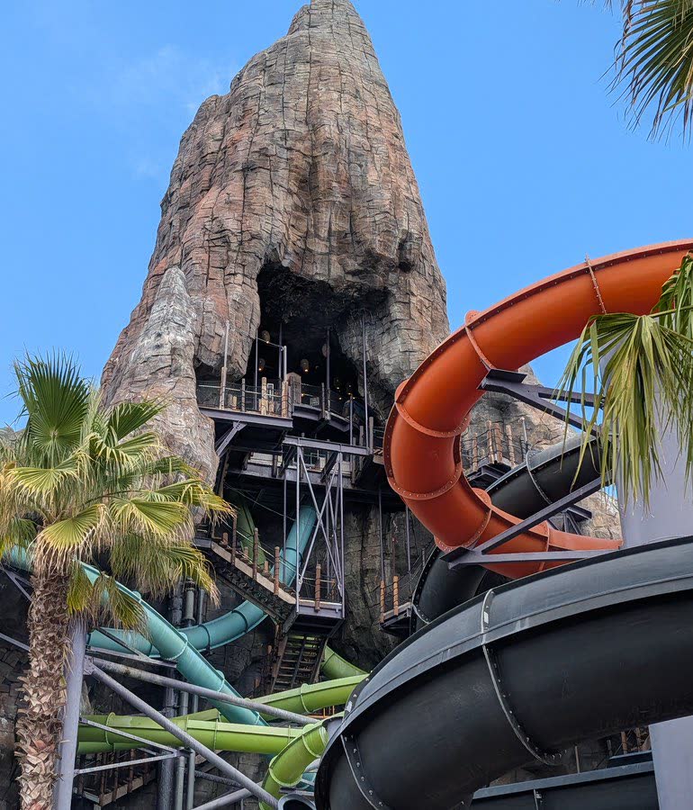 The Krakatau volcano with the orange and teal Punga Racers slide tubes twisting down its side between palm trees