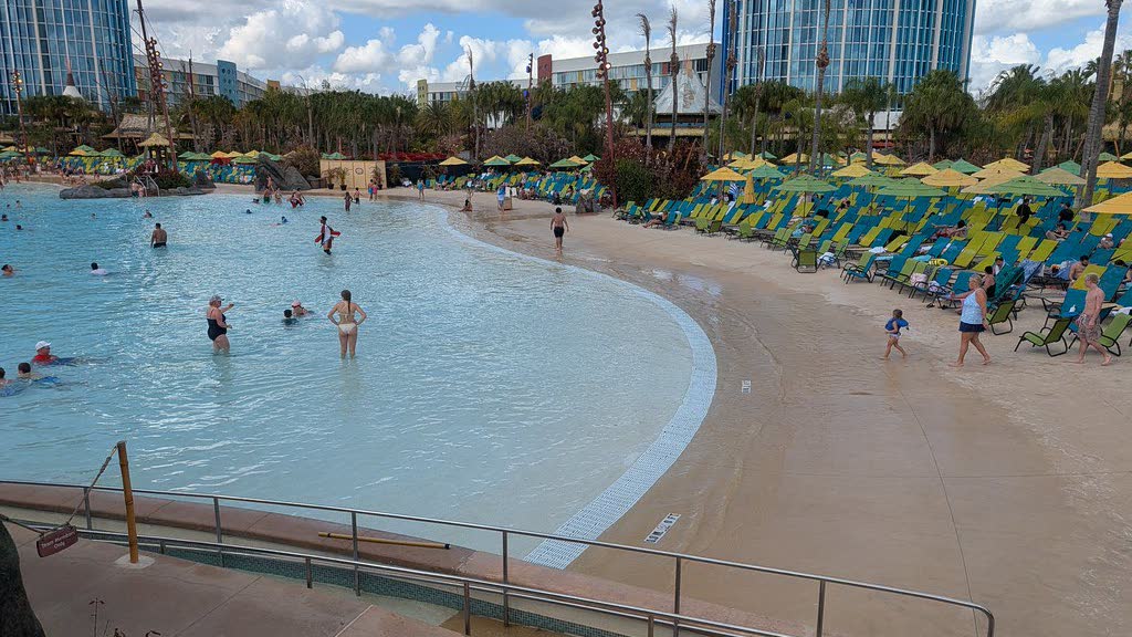 The wide sandy shoreline and wave pool at Waturi Beach, ringed with rows of green and blue loungers and umbrellas
